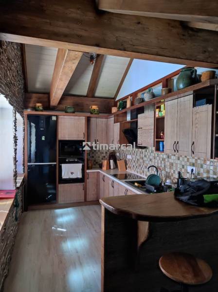 Holzküche in einer Zweizimmerwohnung mit Steindetails und Holzbalken.