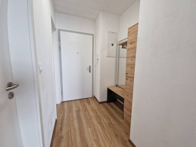 Eingangsflur mit hellen Wänden und Holzboden in einer 2-Zimmer-Wohnung.