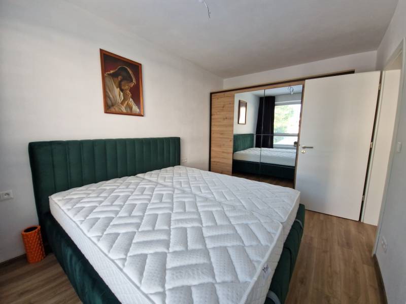 Schlafzimmer in einer 2-Zimmer-Wohnung mit Doppelbett, Gemälde und Einbauschrank.