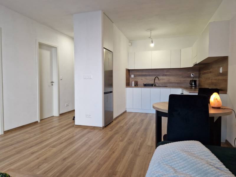 Küche und Essbereich in einer 2-Zimmer-Wohnung mit Holzboden und weißen Möbeln.