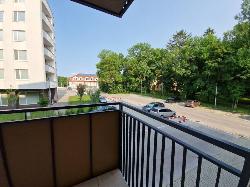 Blick vom Balkon auf die Straße Sadová in Senica, mit Aussicht auf den Parkplatz und das Grün.