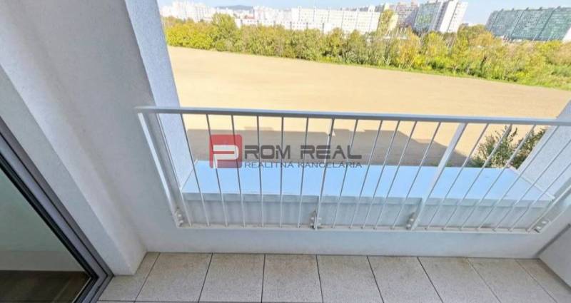 Der Balkon einer 2-Zimmer-Wohnung in der Labutej-Straße, Bratislava V mit Blick auf Grünflächen und Gebäude.
