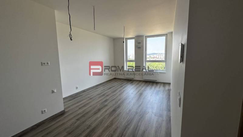 Geräumiges Zimmer in einer 2-Zimmer-Wohnung mit großen Fenstern und Laminatboden.
