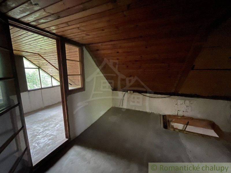 Ein Dachzimmer mit Holzverkleidung und einer verglasten Wand in einem Einfamilienhaus.