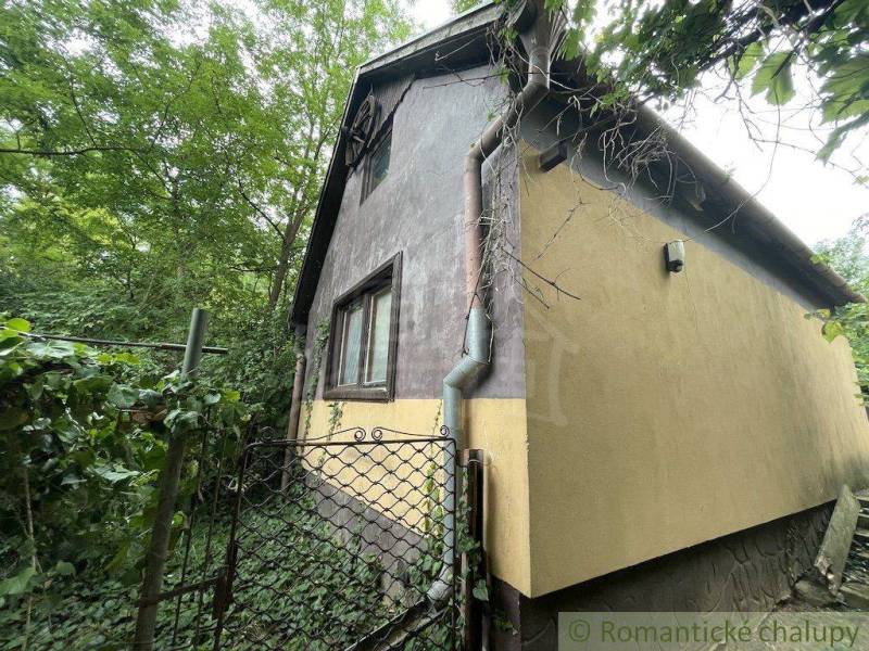 Ein Einfamilienhaus in Branč, umgeben von Grün mit einem Tor und einem Dachrinnensystem.