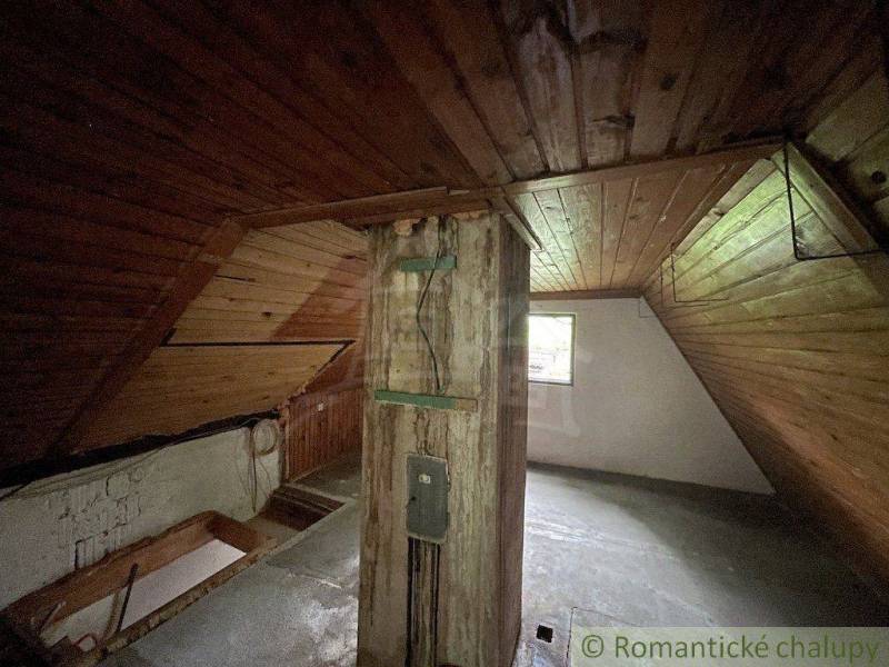 Dachboden in einem Einfamilienhaus mit Holzverkleidung und Balken, erhellt durch ein Fenster.
