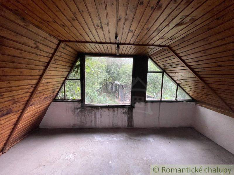 Ein Dachzimmer mit Holzverkleidung und Blick auf den Garten in einem Einfamilienhaus.