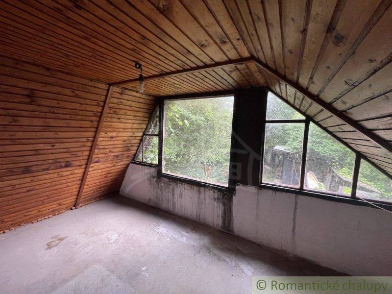Dachgeschosszimmer in einem Einfamilienhaus mit Holzverkleidung und großen Fenstern.