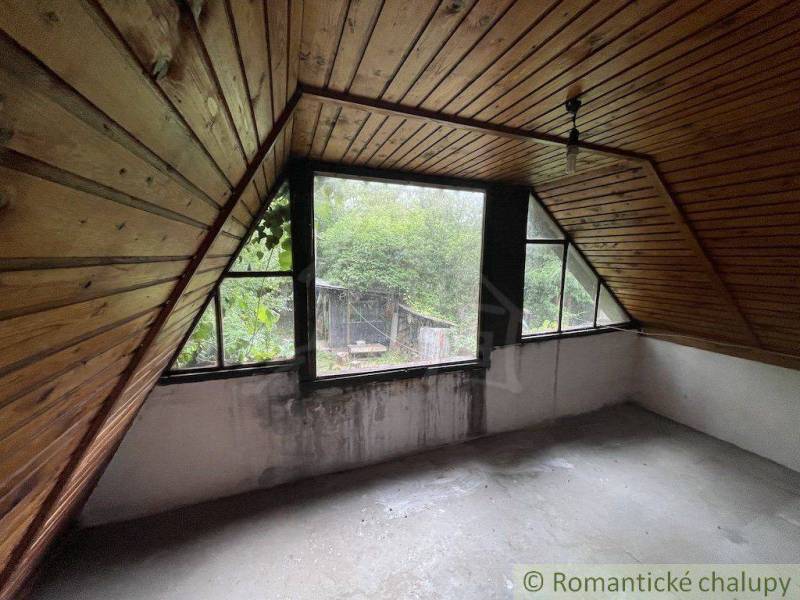 Ein Dachzimmer in einem Einfamilienhaus mit Holzverkleidung und Blick auf den Garten.