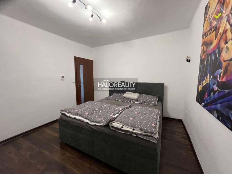 Schlafzimmer in einem Einfamilienhaus mit Bett, dunklem Boden und Bild an der Wand.
