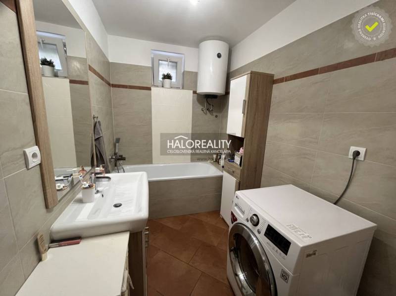 Badezimmer in einem Einfamilienhaus mit Dusche, Waschmaschine und Waschbecken.