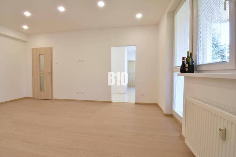 Ein helles Zimmer mit Holzboden in einer 3-Zimmer-Wohnung, beleuchtet mit Deckenleuchten.