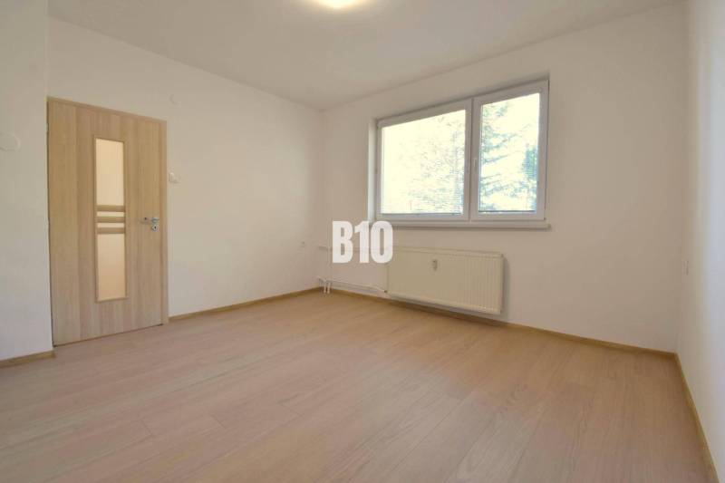 Helles Zimmer mit Holzböden und Fenster in einer 3-Zimmer-Wohnung.