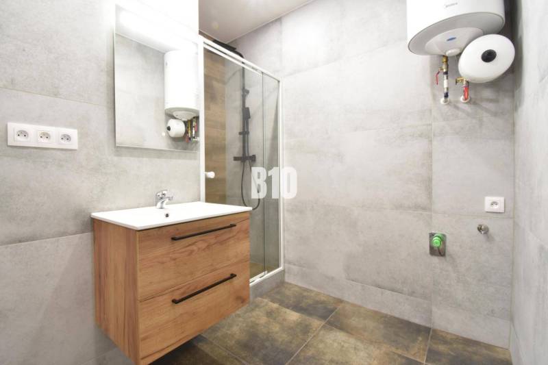 Badezimmer in einer 3-Zimmer-Wohnung mit einem Holzschrank, einer Duschkabine und einem Wassererhitzer.
