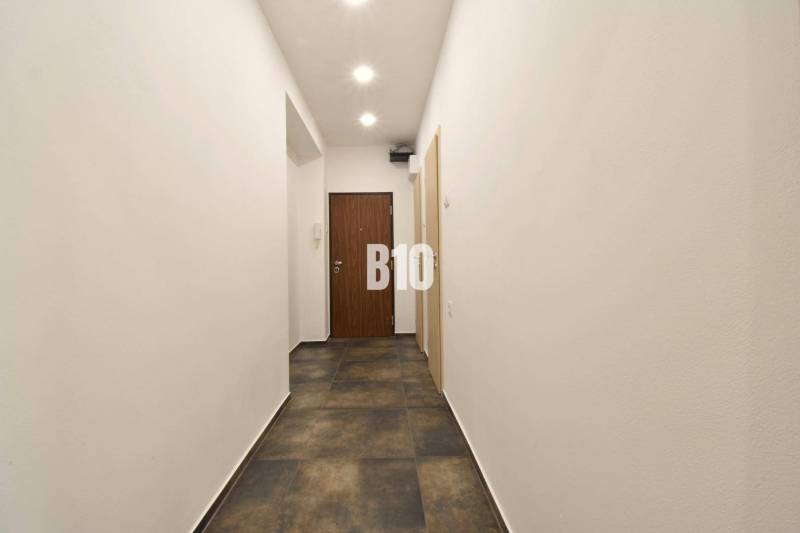 Ein Flur mit weißen Wänden und dunklem Boden in einer 3-Zimmer-Wohnung.