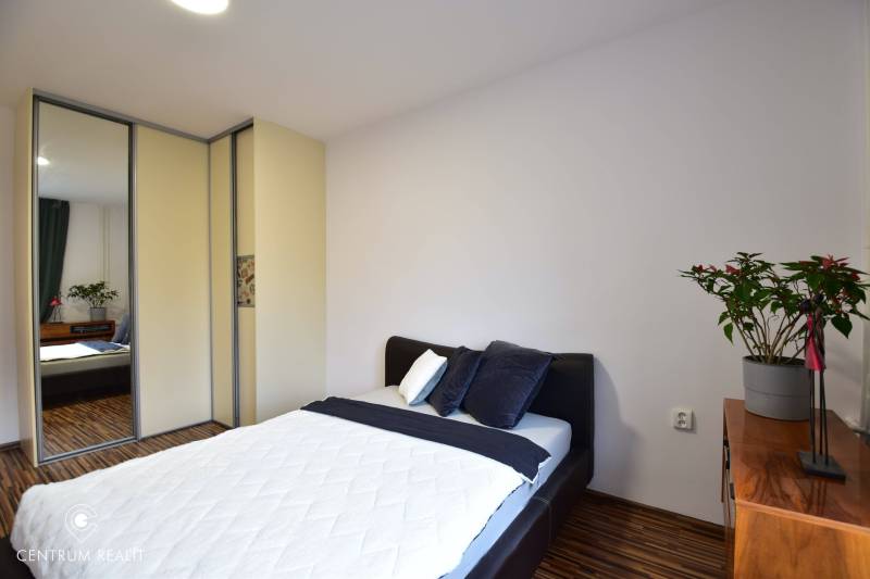 Schlafzimmer in einer 2-Zimmer-Wohnung mit Bett, Schrank und Holzkommode.