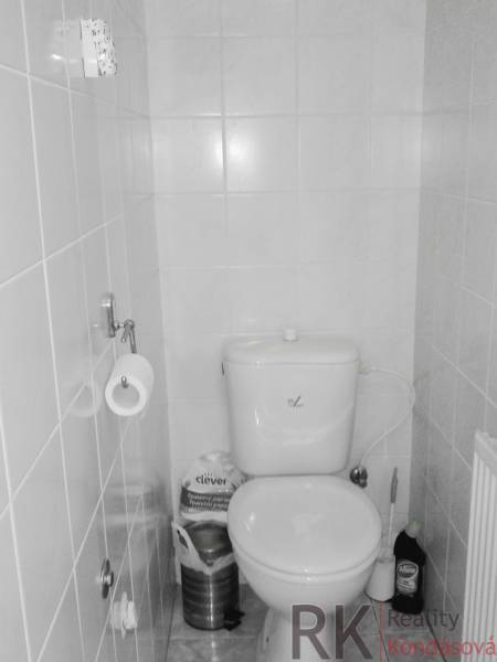 Toilette in einer 2-Zimmer-Wohnung mit gefliesten Wänden und grundlegender Ausstattung.