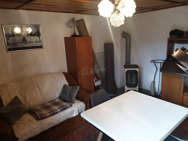 Wohnzimmer in einer Hütte mit Sofa, Tisch und Holzofen.