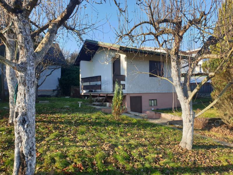Eine Hütte in Mojšova Lúčka in Žilina, umgeben von Bäumen und einem grünen Rasen.