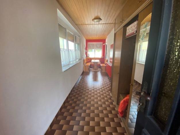 Ein langer Flur in einem Einfamilienhaus mit gemustertem Boden und Holzdecke.