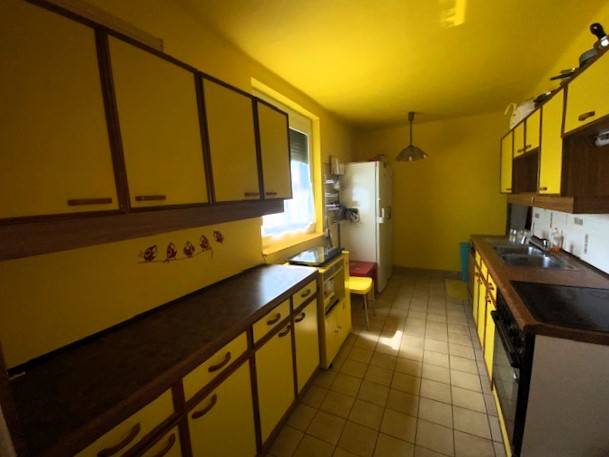 Eine Küche in einem Einfamilienhaus mit gelben Wänden und Schränken, der Raum ist hell und funktional.