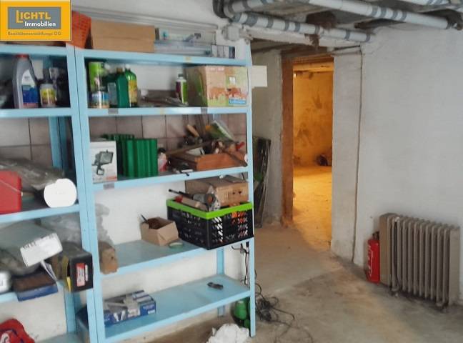 Der Keller des Einfamilienhauses mit einem Regal voller Werkzeuge und Rohre an der Wand.