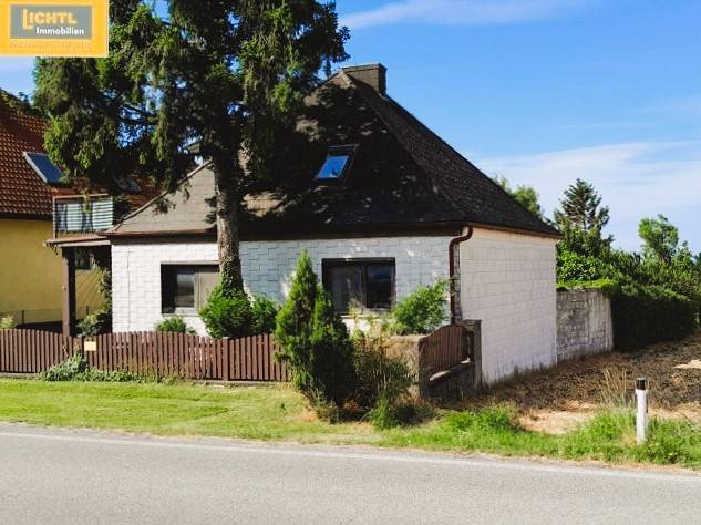 Einfamilienhaus in Hundsheim mit weißer Fassade, Holzzaun und umgebendem Grün.