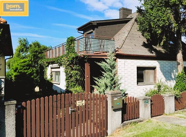 Ein Einfamilienhaus in Hundsheim mit einem Holzzaun, einer Terrasse und üppigem Grün.
