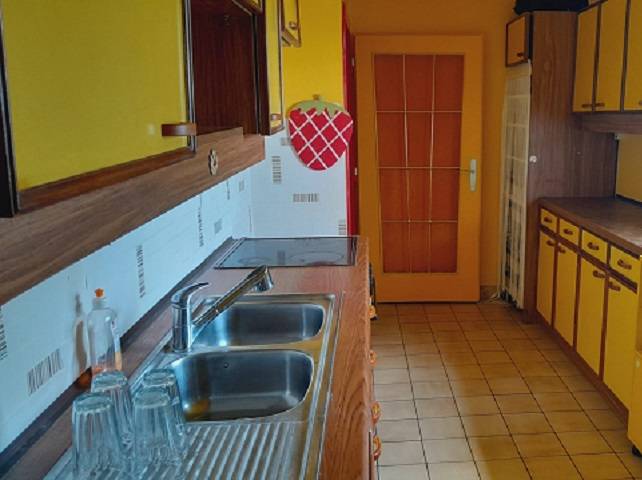 Küche in einem Einfamilienhaus mit gelben Schränken und einem Spülbecken aus Edelstahl.