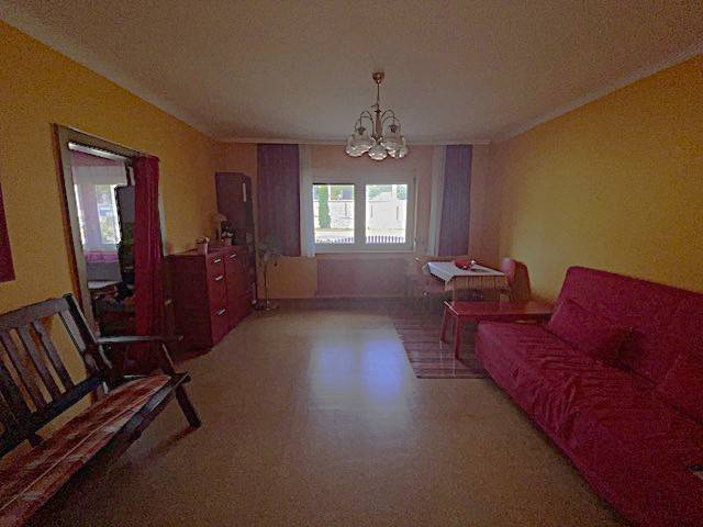 Wohnzimmer in einem Einfamilienhaus mit bunten Wänden, Sofa und Fenster mit Ausblick.