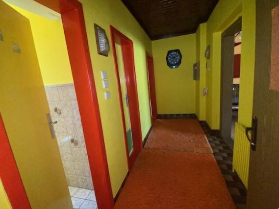 Ein Flur in einem Einfamilienhaus mit klaren gelben Wänden und roten Türen.