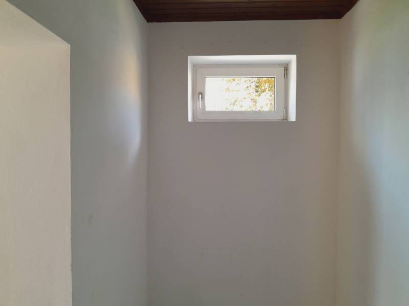 Malé Fenster in engen Geschäftsräumen, weiße Wände, dunkle Decke.