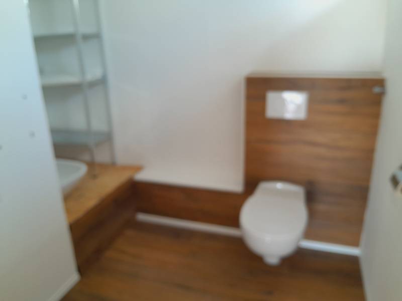 Badezimmer mit Toilette und Holzverkleidung in Geschäftsräumen.