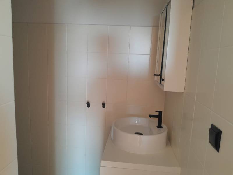 Badezimmergeschäftsräume mit Waschbecken und Schrank in neutralen Tönen.