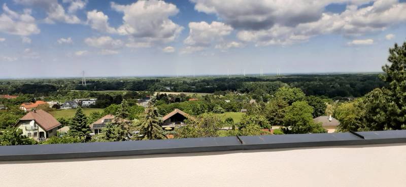 Blick von der Villa in Hainburg an der Donau auf die Landschaft mit Windkraftanlagen und Häusern.