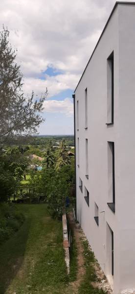 Die weiße Fassade der Villa in Hainburg an der Donau mit Blick auf den Garten und die Bäume.