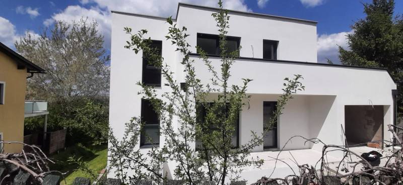 Eine Villa in Hainburg an der Donau mit minimalistischer Fassade und von viel Grün umgeben.