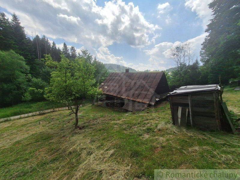 Eine Holzhütte in Zákopčí, umgeben von Wäldern und blauem Himmel.