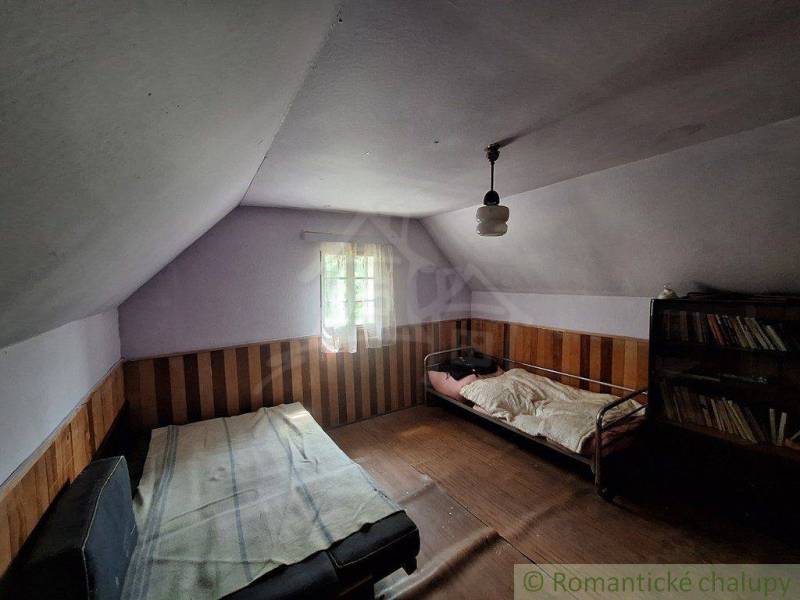 Ein Zimmer in einer Hütte mit Betten und einem Bücherregal, Holzwandverkleidung.