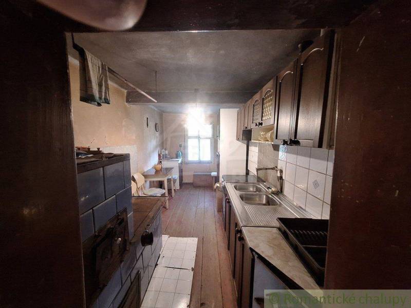 Eine Küche in einer Hütte mit Holzverkleidung, einem Kachelofen und einem Waschbecken.