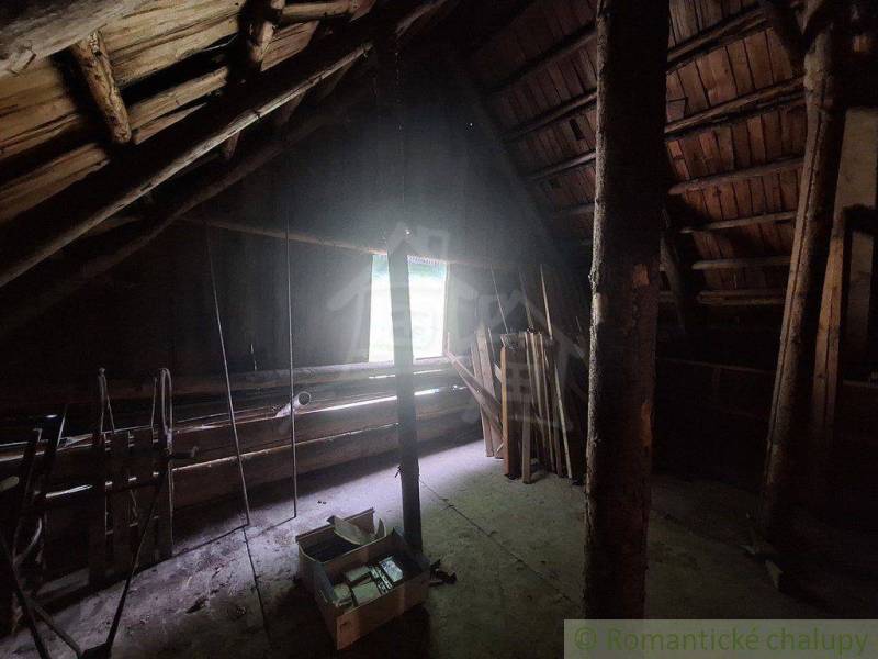 Das Dachgeschoss der Hütte mit Holzbalken und einem Fenster, das den Raum beleuchtet.