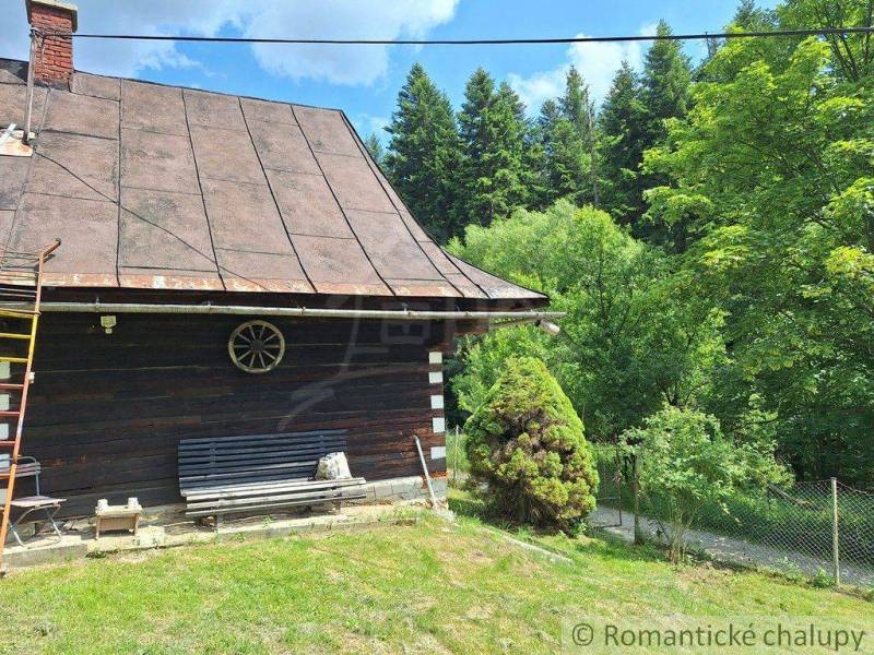 Eine Hütte in Zákopčí, umgeben von Wäldern, mit einer Bank und Holzelementen.