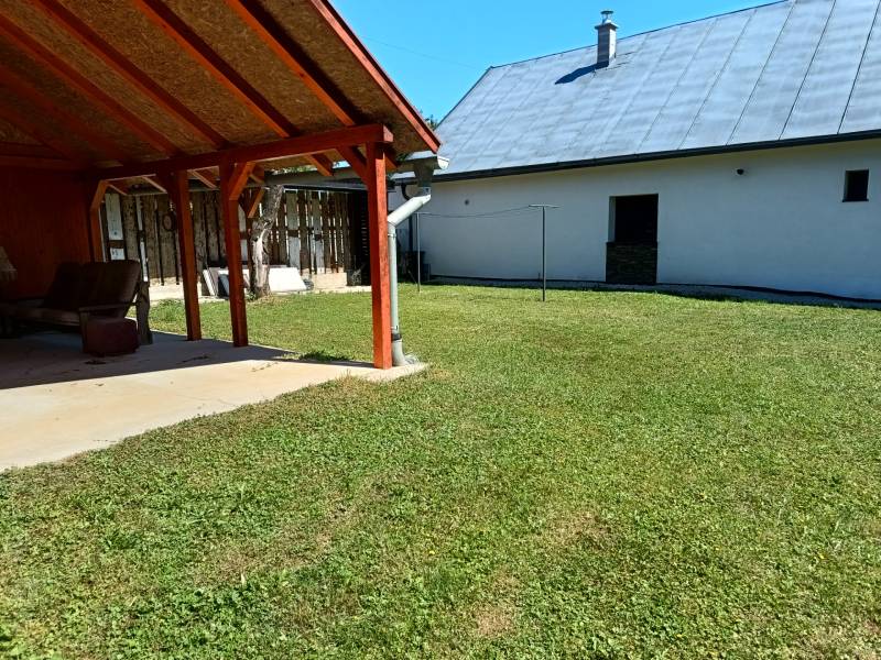 Garten bei der Hütte in Tužina mit Unterstand und Rasen an einem sonnigen Ort.