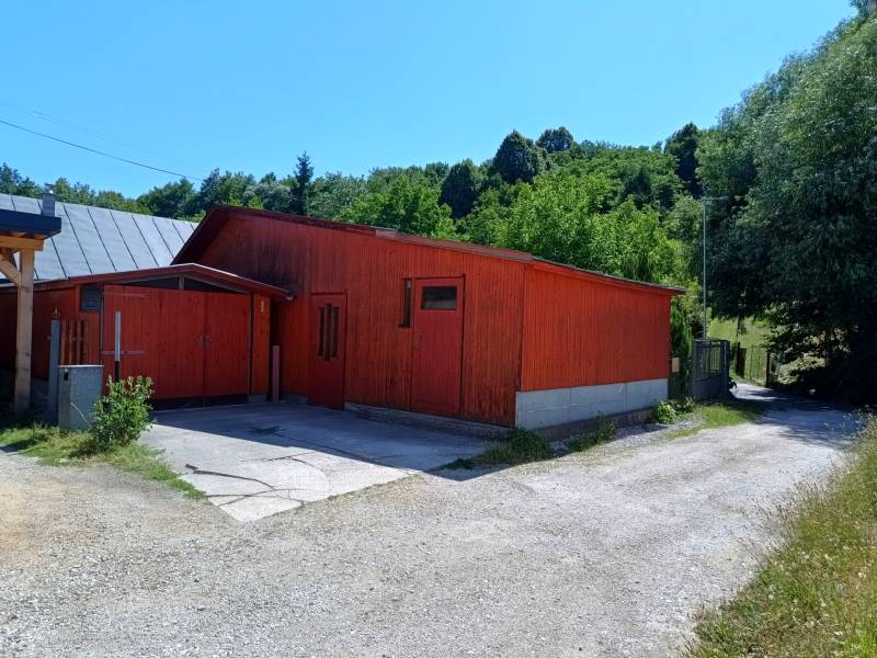 Eine Hütte in Tužina mit einem Satteldach, umgeben von Grün.