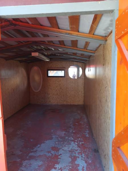 Interieur einer Hütte mit Holzkonstruktion und Fenstern.