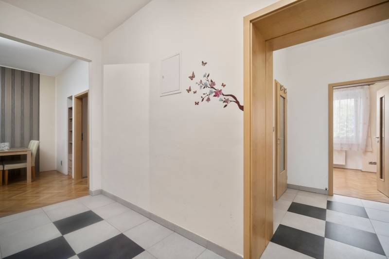 Eingangshalle in einer 3-Zimmer-Wohnung mit Blumendekoration an der Wand und Holztüren.