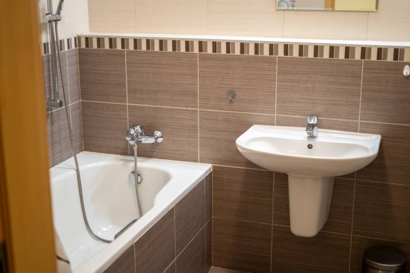 Badezimmer mit Waschbecken und Badewanne in einer 3-Zimmer-Wohnung, dezente Wandfliesen.