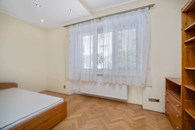Helles Schlafzimmer mit Vorhängen und Holzmöbeln in einer 3-Zimmer-Wohnung.