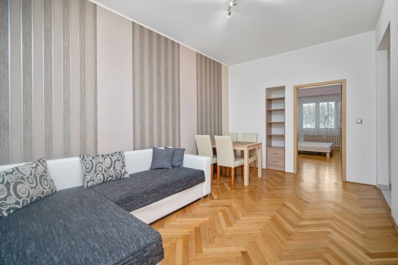 Wohnzimmer mit orangefarbenen Holzmöbeln, Sofa und Esstisch in einer 3-Zimmer-Wohnung.