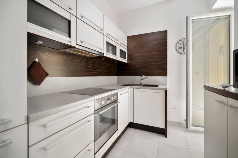 Küche in einer 3-Zimmer-Wohnung mit weißen Schränken und eingebauten Geräten.
